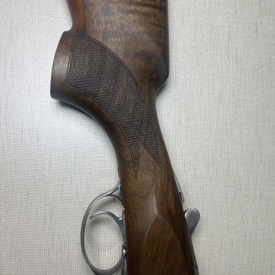 Coronha de arma de fogo em madeira castanha com textura quadriculada e gatilho metálico