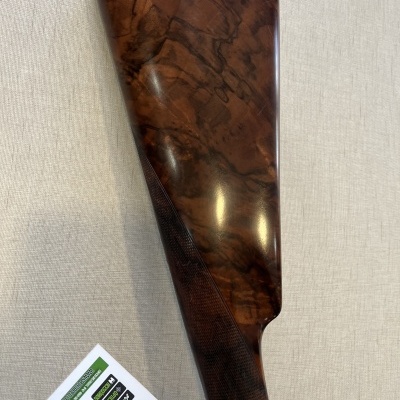 Parte da coronha de espingarda em madeira polida com etiqueta branca