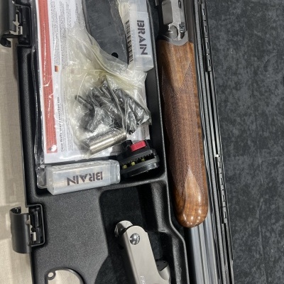 Estojo aberto com peças de espingarda e acessórios organizados no interior moldado