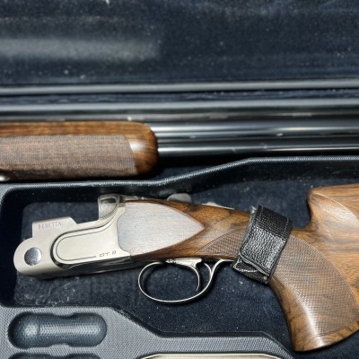 Espingarda desmontada com coronha em madeira e partes metálicas dentro de estojo acolchoado preto.