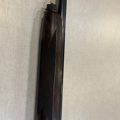 Espingarda com coronha de madeira escura e cano preto encostada na parede