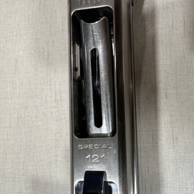 Parte de arma metálica prateada com inscrições SPECIAL 121