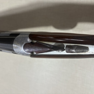 Arma de caça com coronha de madeira castanha e metal prateado decorado