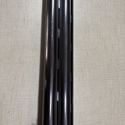 Tubo duplo metálico preto com fendas, fundo bege texturizado