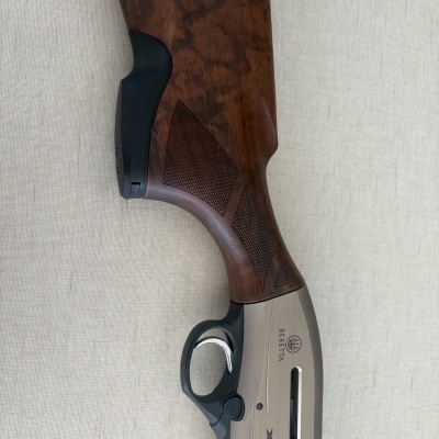 Coronha de madeira e parte metálica cinza de uma espingarda Beretta com texto visível