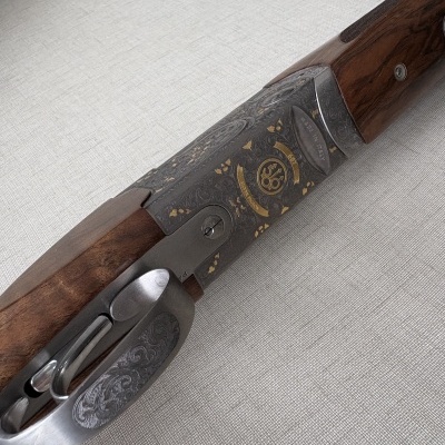 Parte de uma arma de caça em madeira e metal com gravações douradas