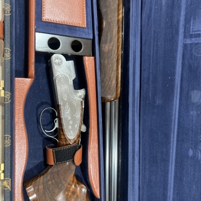 Espingarda de caça numa mala forrada a tecido azul escuro e detalhes em couro castanho