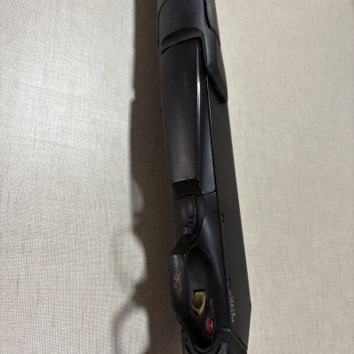 Parte de uma arma de fogo preta com gatilho e detalhes em cinza escuro