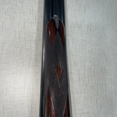 Frontal de arma de fogo com madeira escura entalhada e canos pretos