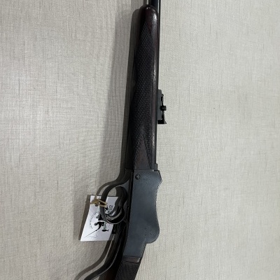 Rifle de cano longo com coronha em madeira escura e corpo metálico preto