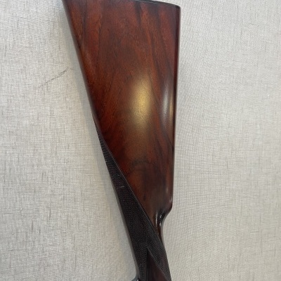 Coronha de espingarda em madeira castanho-escuro com padrão quadriculado na empunhadura