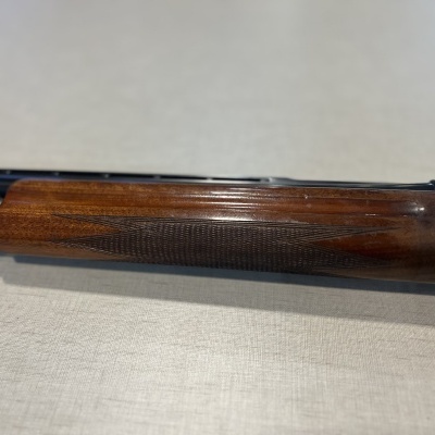 Parte dianteira de espingarda com madeira escura e cano preto