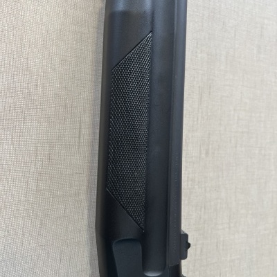 Parte preta de arma de fogo com textura antiderrapante em fundo cinzento