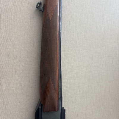 Espingarda com coronha castanha e corpo metálico preto num fundo bege