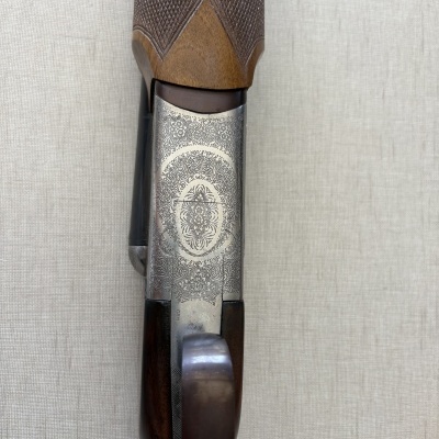 Parte superior com coronha de madeira e metal gravado de uma espingarda