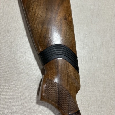 Parte traseira e punho de espingarda em madeira castanha com detalhes em borracha preta