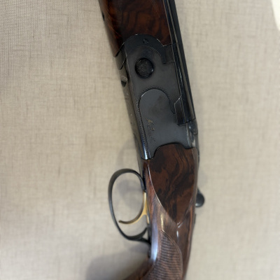 Arma de fogo estilo espingarda com madeira escura e metal preto fosco com gravação