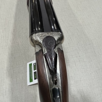 Espingarda de canos duplos em metal prateado e madeira escura com gravuras decorativas