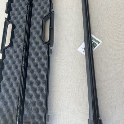 Capa rígida preta com espuma e objeto metálico longo preto sobre superfície clara