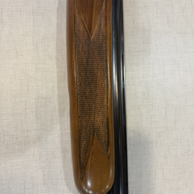 Parte de espingarda com alça de madeira trabalhada e cano metálico preto