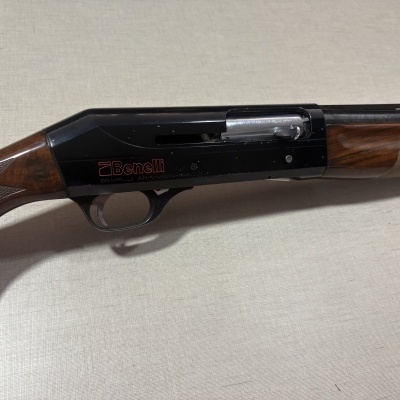 Espingarda Benelli com acabamentos em madeira e metal sobre tecido bege