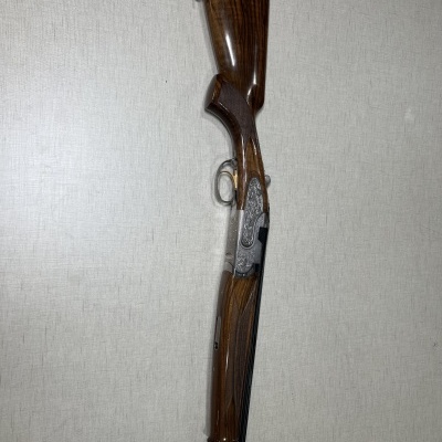 Espingarda over-and-under com madeira polida castanho escuro e detalhes metálicos gravados