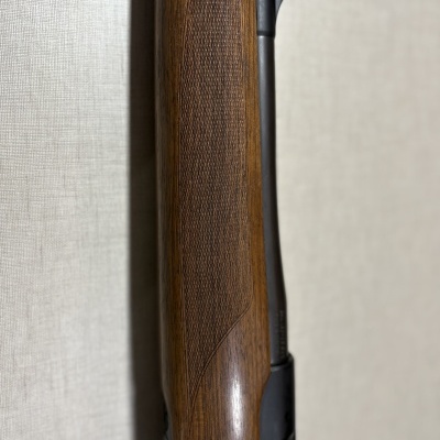 Coronha de espingarda em madeira castanha com textura e detalhes em metal preto