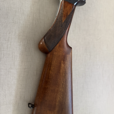Espingarda com coronha em madeira castanha e metal prateado.