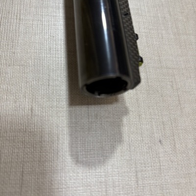 Objeto cilíndrico preto com textura sobre superfície têxtil bege