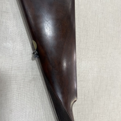 Cola de espingarda de madeira escura polida sobre tecido bege