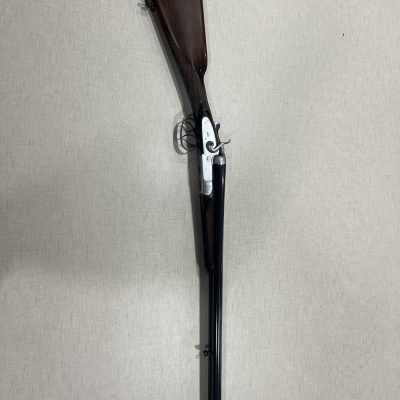 Espingarda de canos duplos com coronha em madeira castanha e armação metálica prateada