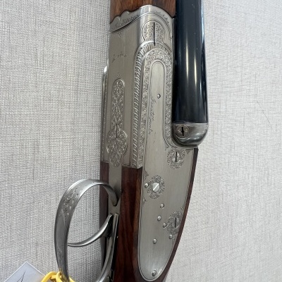 Espingarda de cano duplo em madeira e metal prateado com detalhes e etiqueta amarela