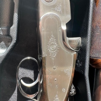 Parte metálica de arma de fogo com decoração e cabo de madeira em caixa acolchoada preta