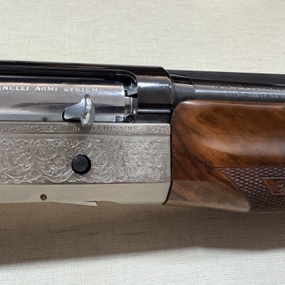 Parte metálica prateada e madeira castanha de espingarda Benelli Armi System com gravações e texto