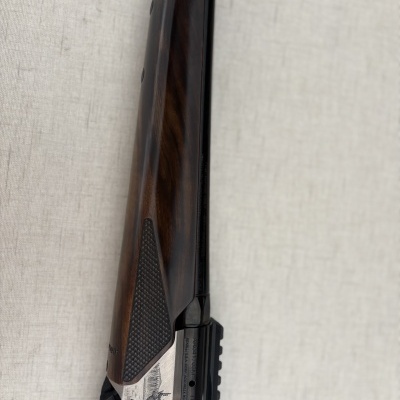 Rifle com coronha de madeira escura e detalhes metálicos gravados