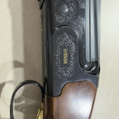 Espingarda com madeira castanha e metal preto gravado com a marca BERETTA