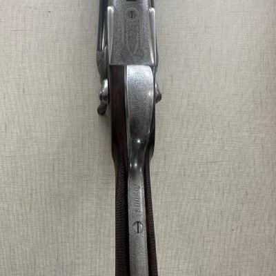 Espingarda de cano duplo com coronha de madeira e detalhes em metal gravado.