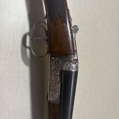 Espingarda de canos duplos com madeira escura e detalhes metálicos gravados