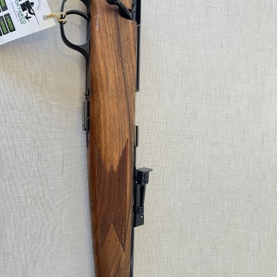 Carabina com coronha de madeira castanha e mira ajustável com fundo de tecido bege