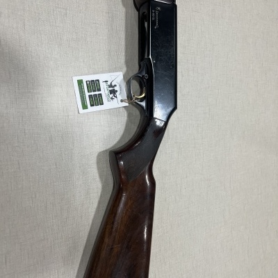 Espingarda de madeira e metal preto com etiqueta pendurada