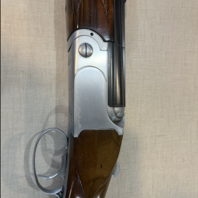 Espingarda clássica com coronha de madeira escura e metal prateado