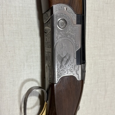 Espingarda Beretta com punho de madeira e detalhes metálicos gravados