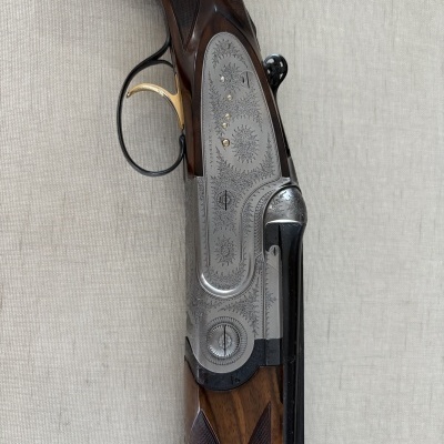 Parte de arma de caça com detalhes em madeira e metal gravado