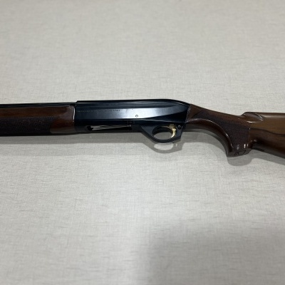 Espingarda com madeira castanha e metal preto sobre superfície clara