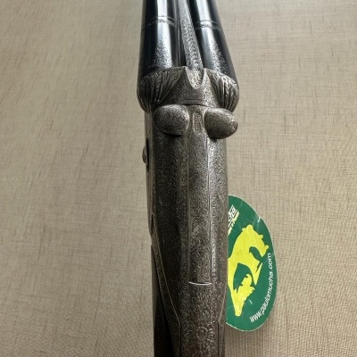 Espingarda dupla com detalhe metálico em forma de rosto e etiqueta verde amarela