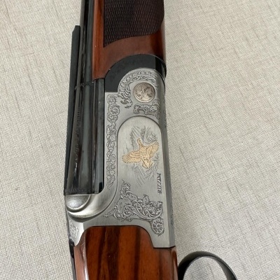 Espingarda de cano duplo com gravações decorativas e acabamento em madeira castanha