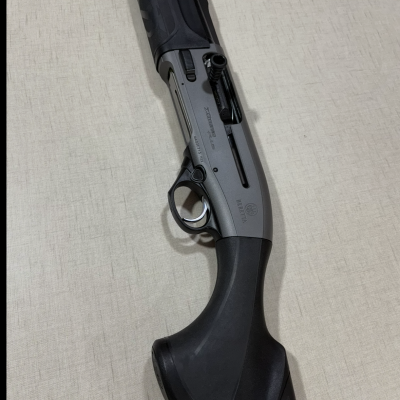 Espingarda Beretta AL391 Urika em metal cinzento com empunhadura preta sobre tecido claro.