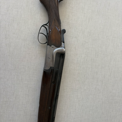 Espingarda de canos paralelos com coronha e guarda-mão em madeira escura, armação metálica gravada