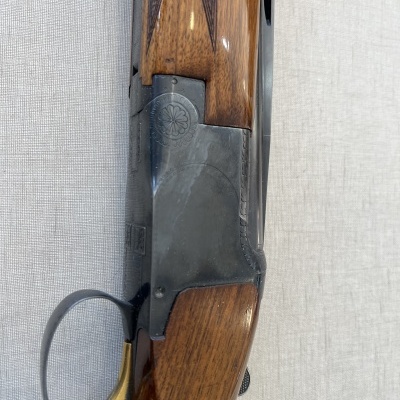 Espingarda com armação metálica preta, detalhe floral, punho em madeira castanha e gatilho dourado