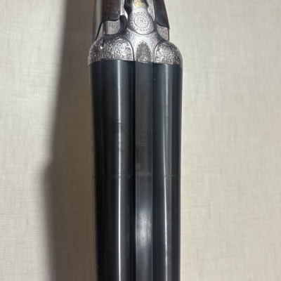 Canos duplos de espingarda com gravações florais em metal prateado e madeira escura